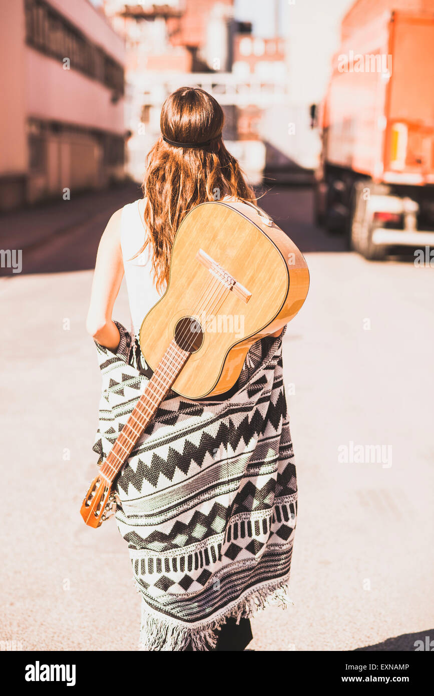 Mujer joven con la guitarra sobre su espalda caminando en la calle  Fotografía de stock - Alamy