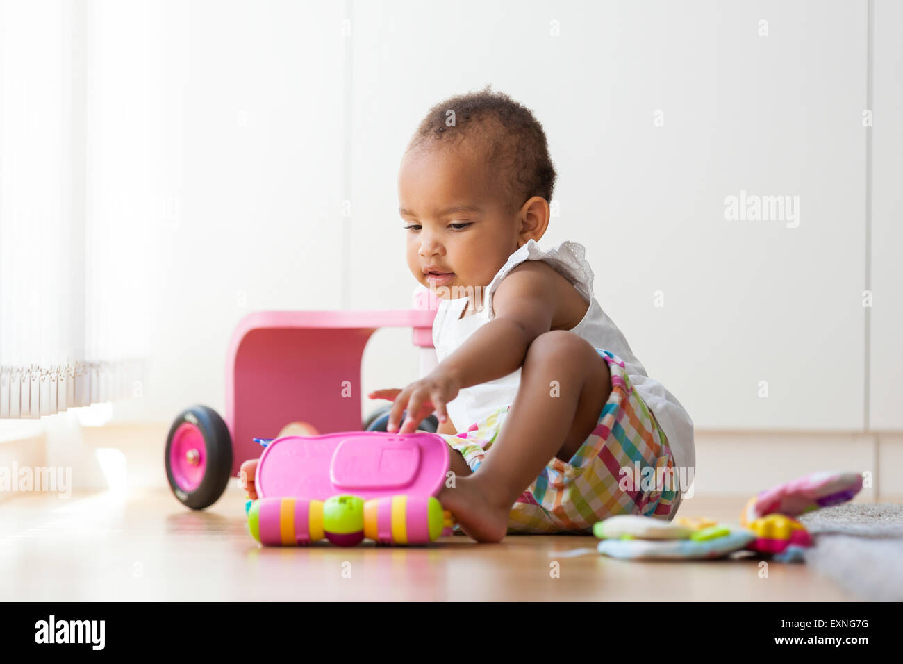 Retrato de poco Afroamericanos niña sentada en el suelo y jugar - negros Foto de stock