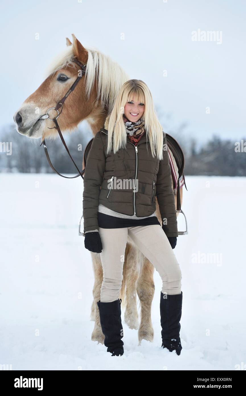 Mujer joven con caballos Haflinger en la nieve Foto de stock