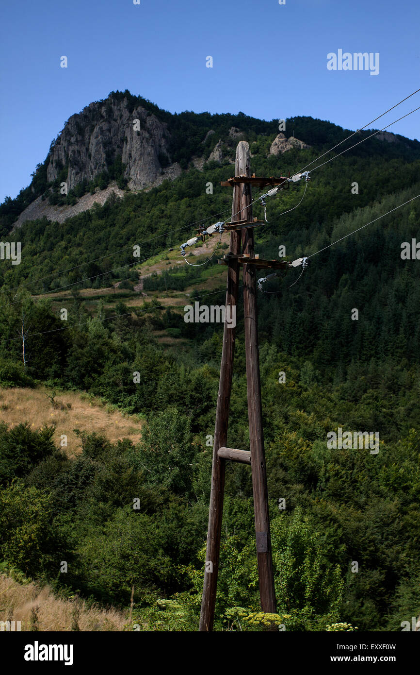 Poste eléctrico de madera antigua entre las crestas de las montañas Foto de stock