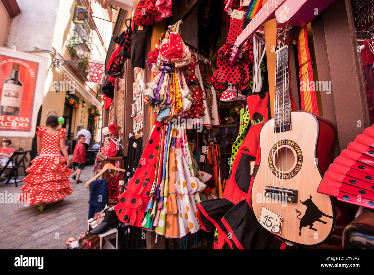 Chica en sevilla vestidos tradicionales pasando tienda de venta barata  guitarras españolas, abanicos y vestidos de flamenco de Sevilla en esta  turística Fotografía de stock - Alamy