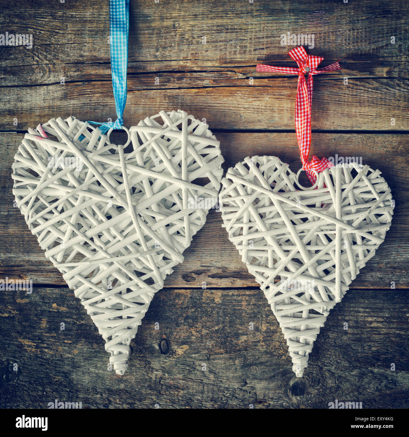 Dos corazones de mimbre colgado en la pared de madera antigua. Foto de stock