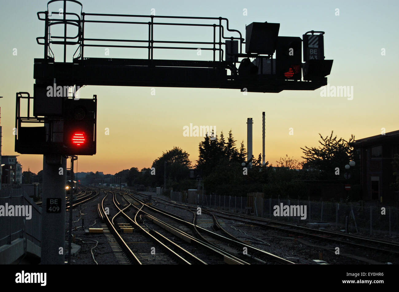 Una señal de parada, de color rojo, junto a las líneas de ferrocarril con rumbo oeste al atardecer. Estación de tren de Basingstoke, Hampshire, Reino Unido. Foto de stock