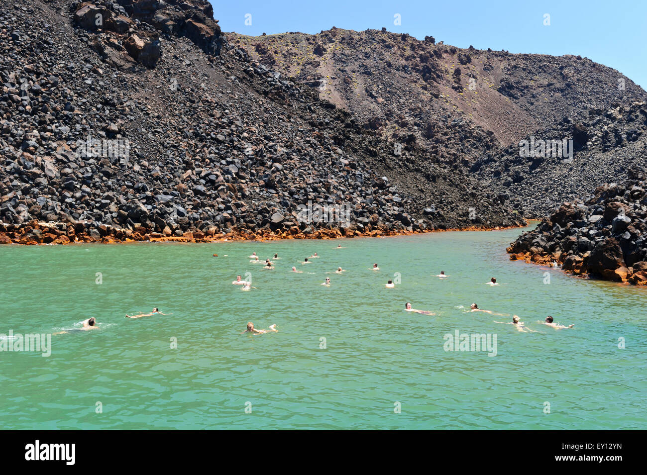 Los turistas nadando en las aguas termales cerca del volcán isla cerca de Santorini, Grecia Fotografía de stock -
