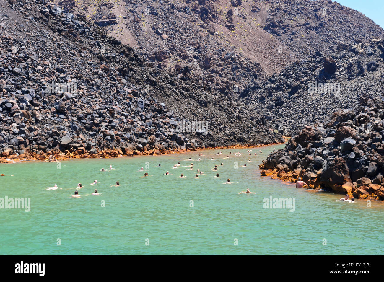 Los turistas nadando en las aguas termales cerca del volcán isla cerca de Santorini, Grecia Fotografía de stock -