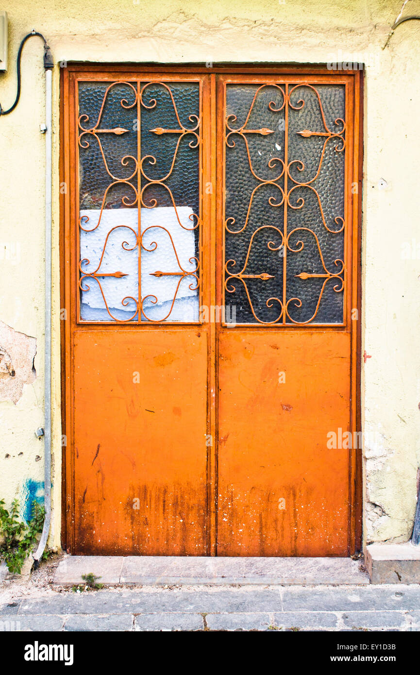 Una puerta doble de color naranja pintado en un muro de piedra Foto de stock