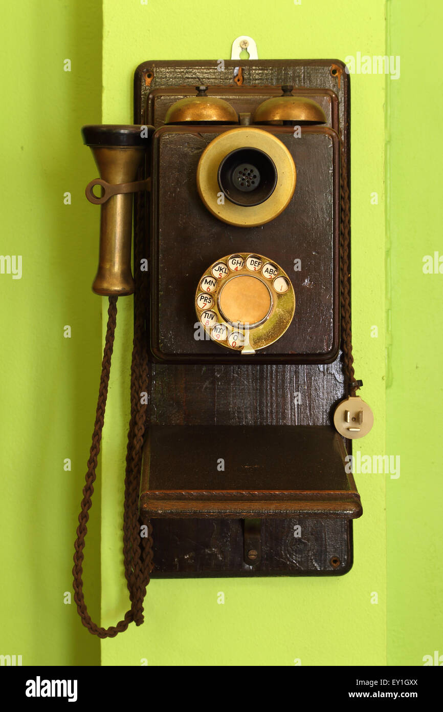 Clásicos de madera viejo teléfono colgado en la pared verde Foto de stock