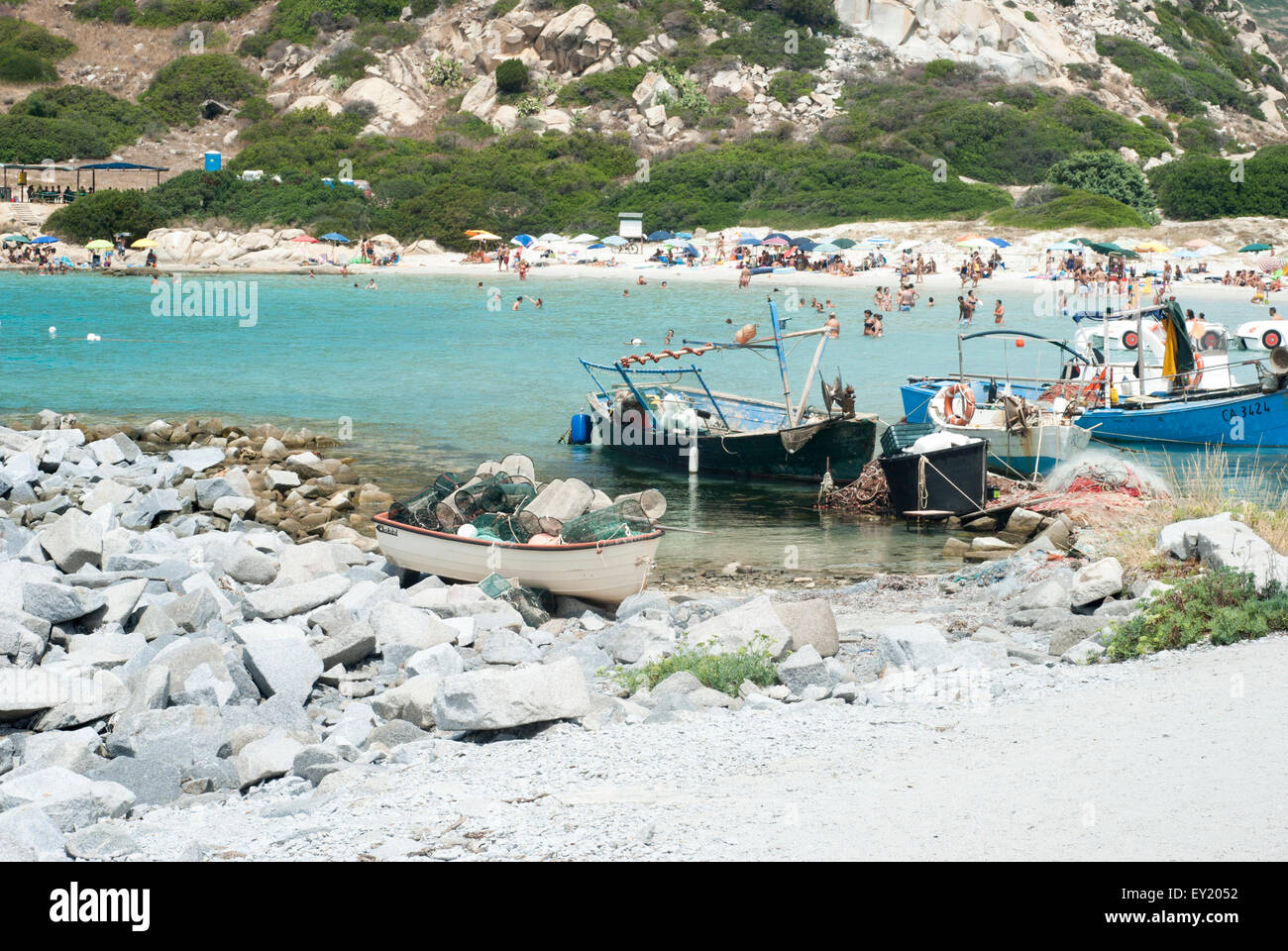 Personas no identificadas en la playa, con el mar azul turquesa, los barcos en verano en julio en Villasimius, Cerdeña, Italia Foto de stock