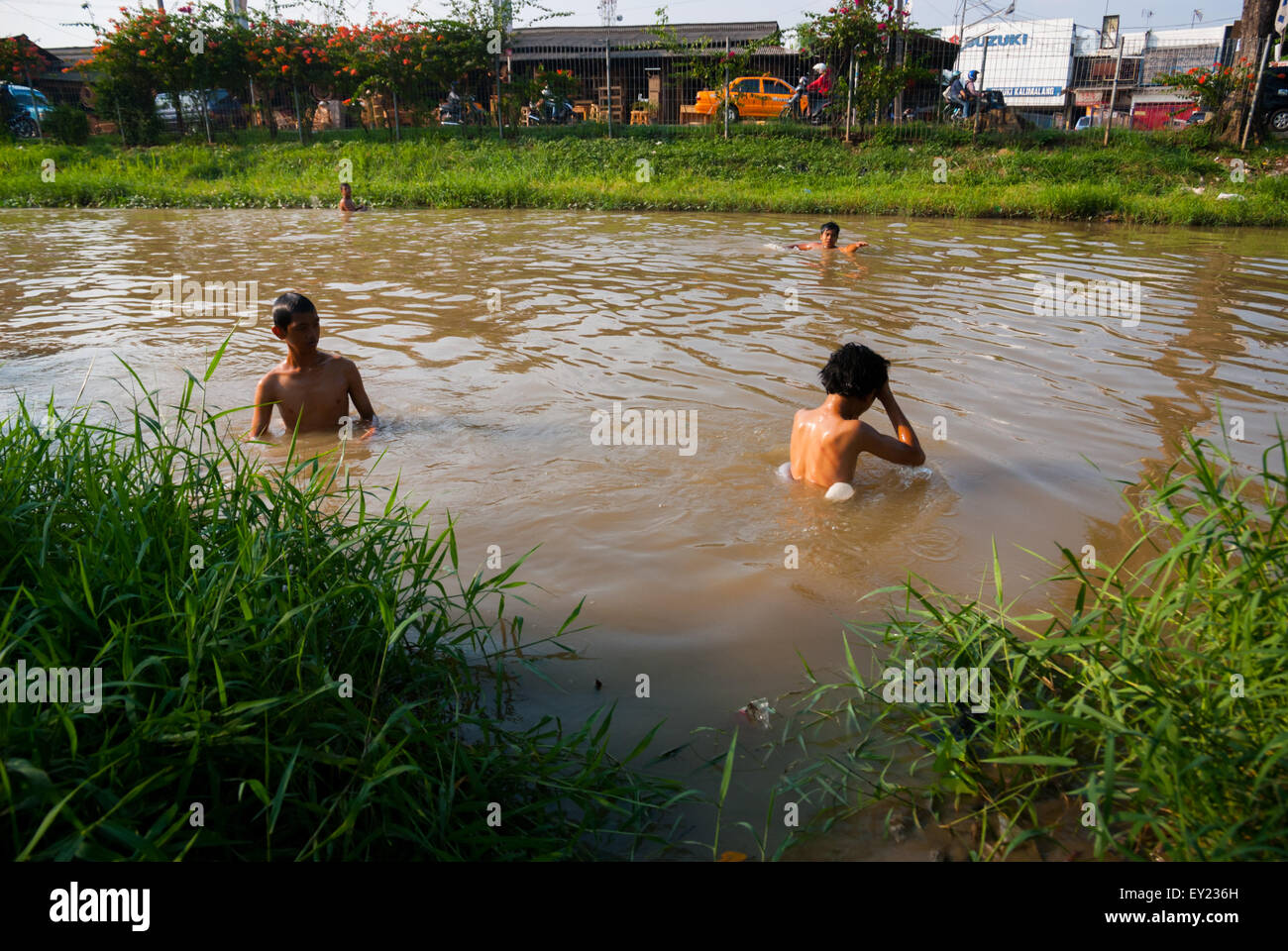 Niños nadando en el canal Kalimalang (canal Tarum Barat) que es un suministro para instalaciones de procesamiento de agua en Yakarta, Indonesia. Foto de stock