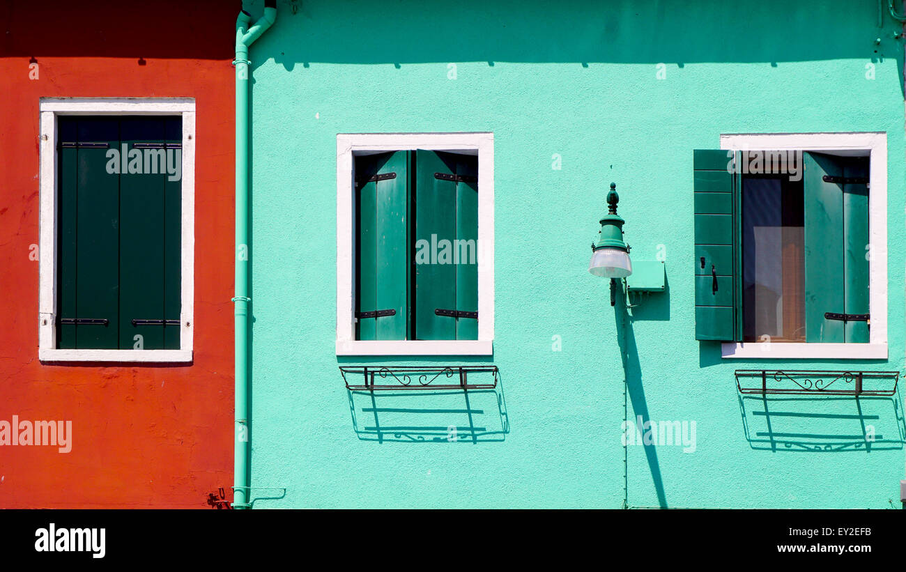 Pared verde y rojo con ventanas la construcción de viviendas en Burano, Venecia, Italia Foto de stock