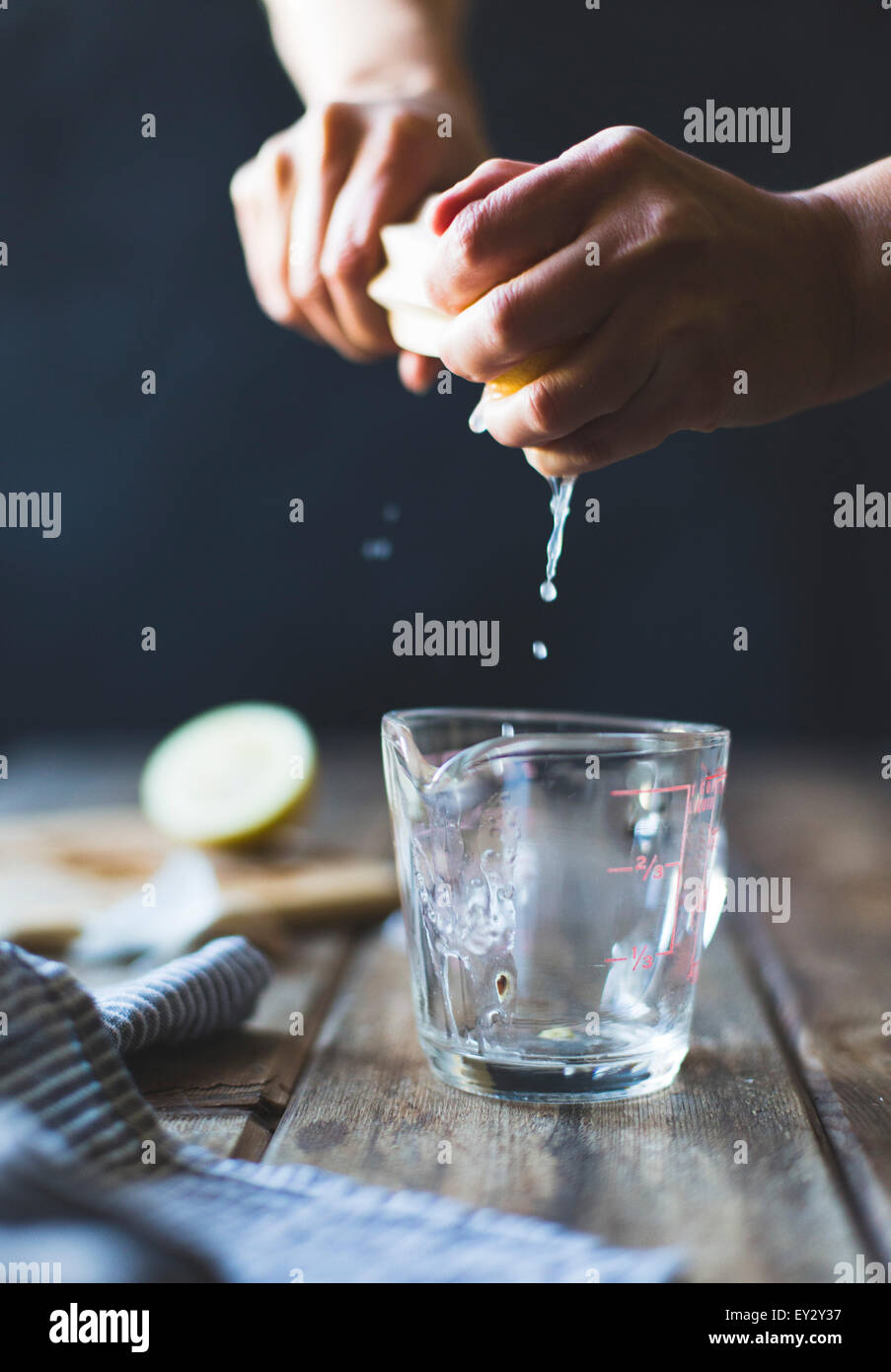 Exprimir el zumo de limón en una jarra medidora. Foto de stock