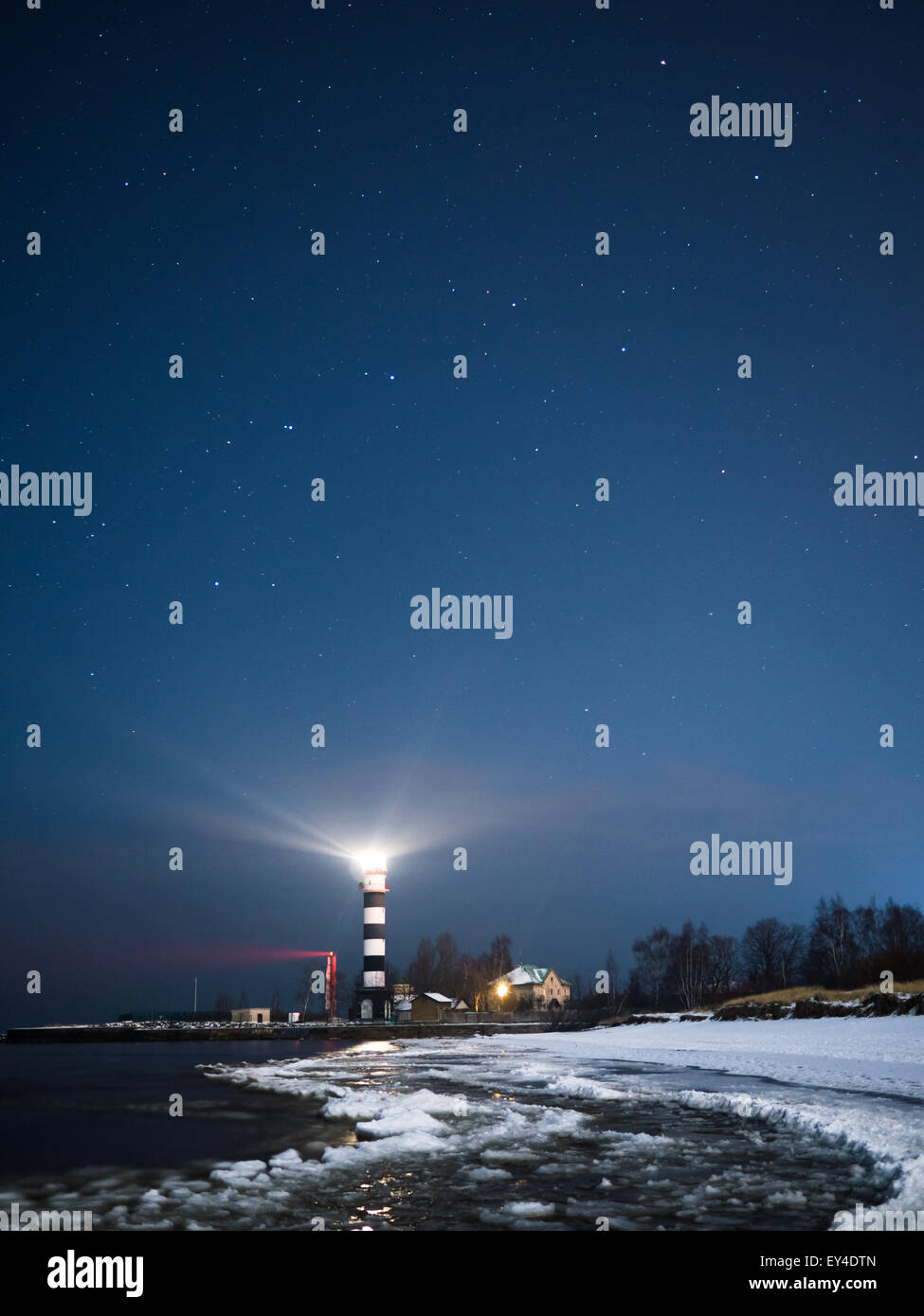 Faro en Riga una noche estrellada con el mar Báltico congelado Foto de stock