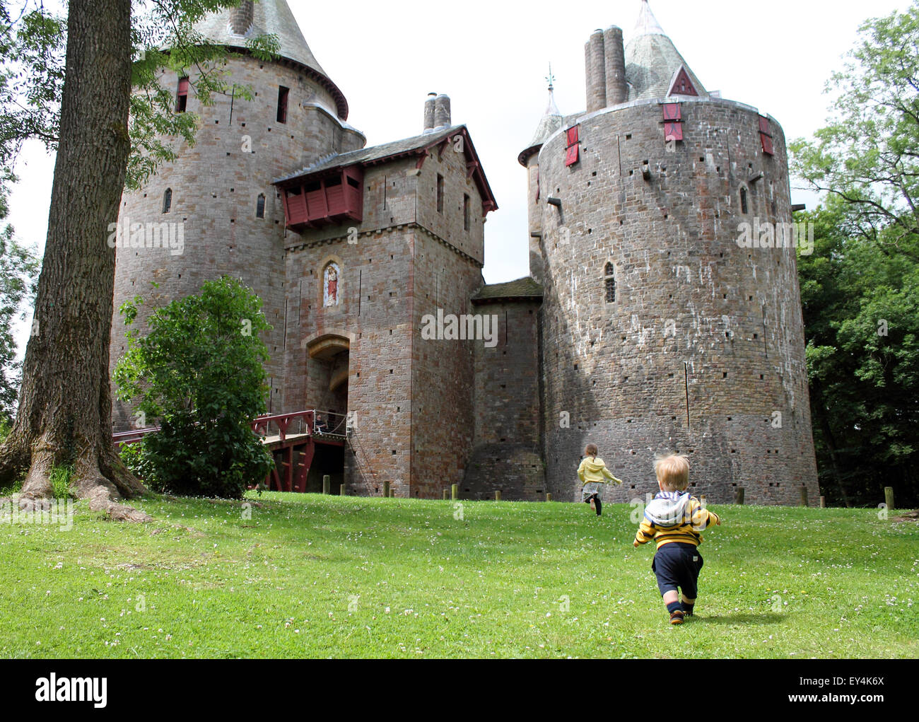Chico y chica corriendo hacia el castillo o Castell Coch, Cardiff, Gales del Sur, Reino Unido Foto de stock