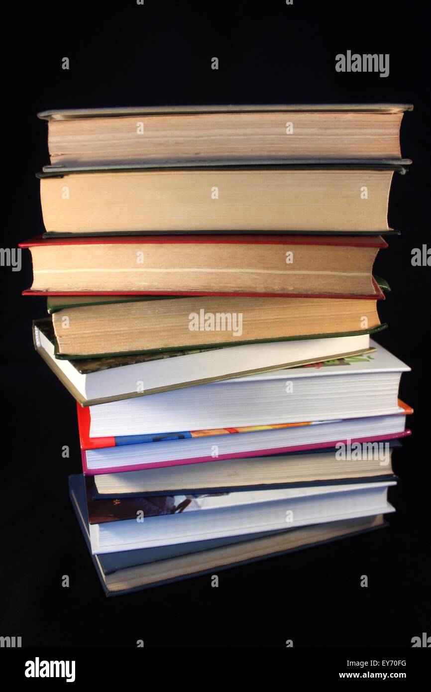 Montón de viejos y nuevos libros sobre un fondo negro Foto de stock