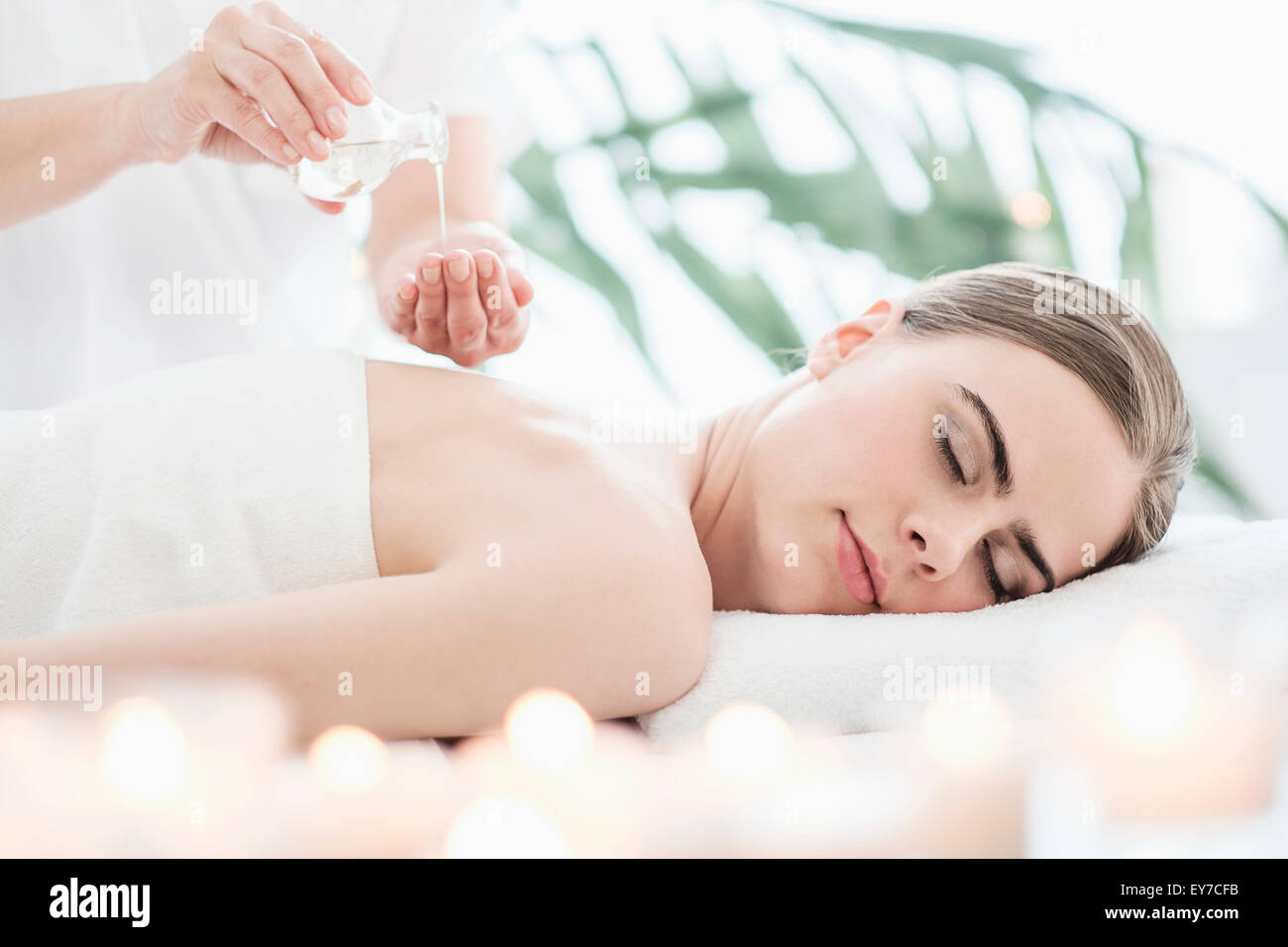 Poner aceite de masaje terapeuta joven en spa Foto de stock