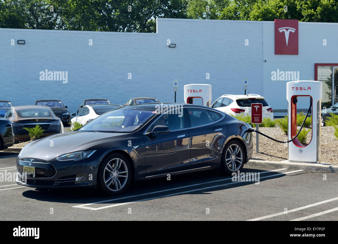 Estación de carga de coches eléctricos con un sedán Tesla enchufado. Tesla concesionario, Paramus, NJ Foto de stock