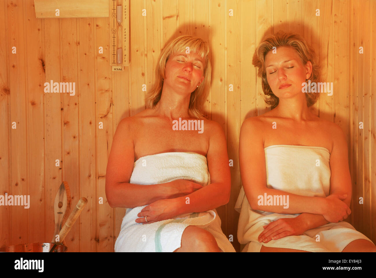 Dos mujeres sentadas dentro de sauna de madera tradicional en Suecia Foto de stock