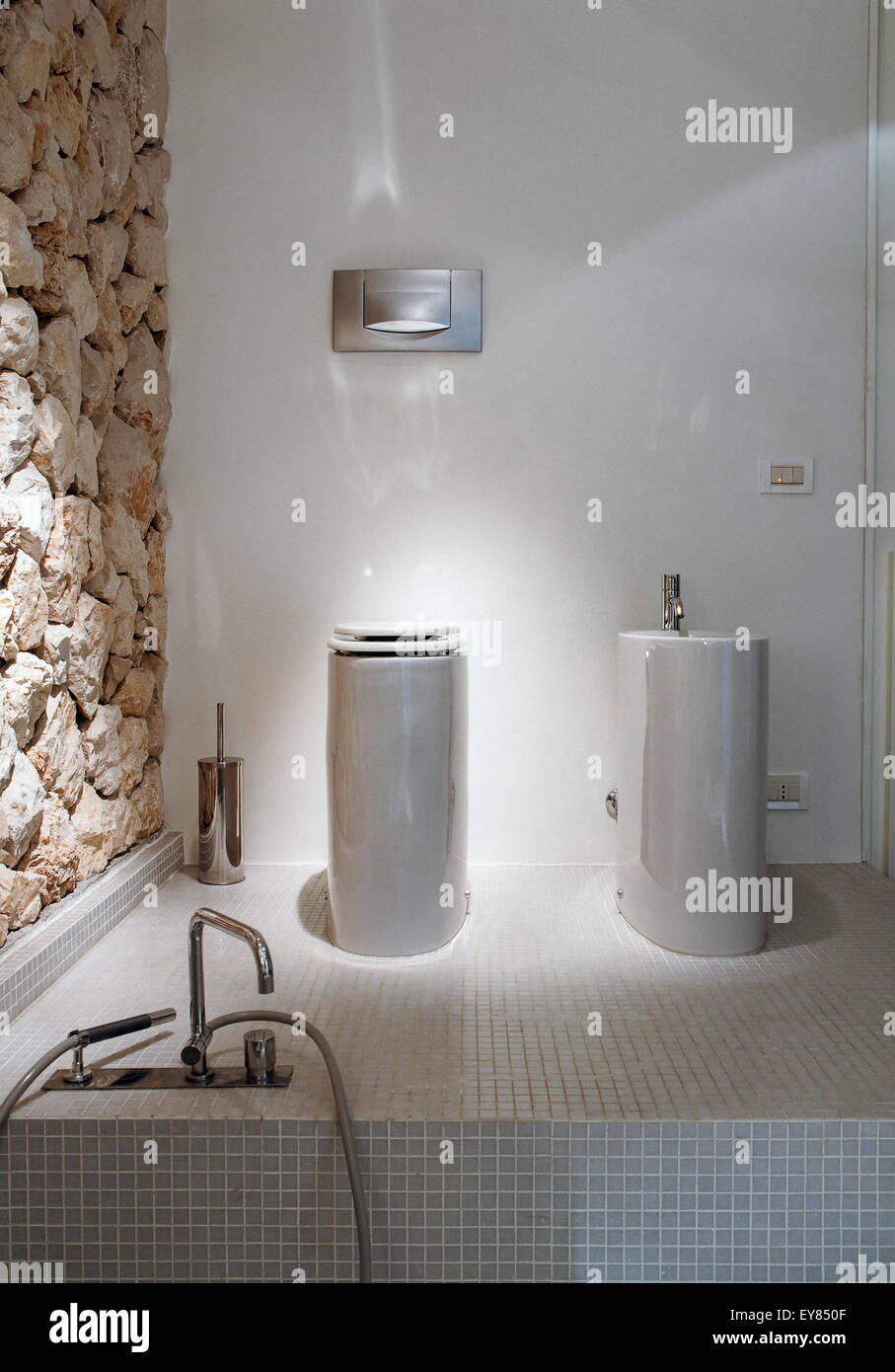 Detalle de la porcelana sanitaria en el baño moderno cuyo piso está revestido con mosaicos en primer plano el grifo de la bañera Foto de stock