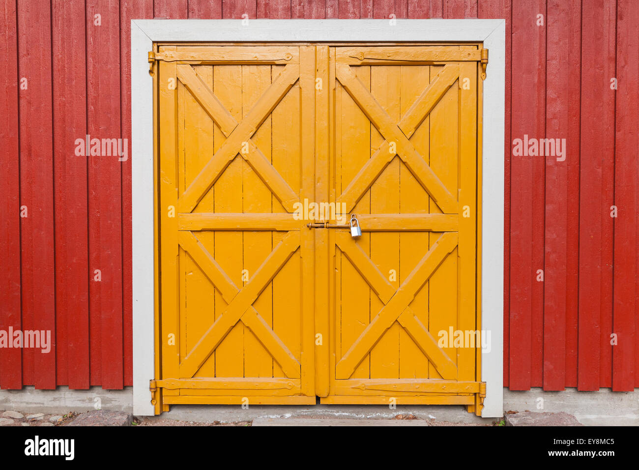 Puerta de madera amarilla bloqueado en rojo la pared de fondo, textura fotográfica Foto de stock