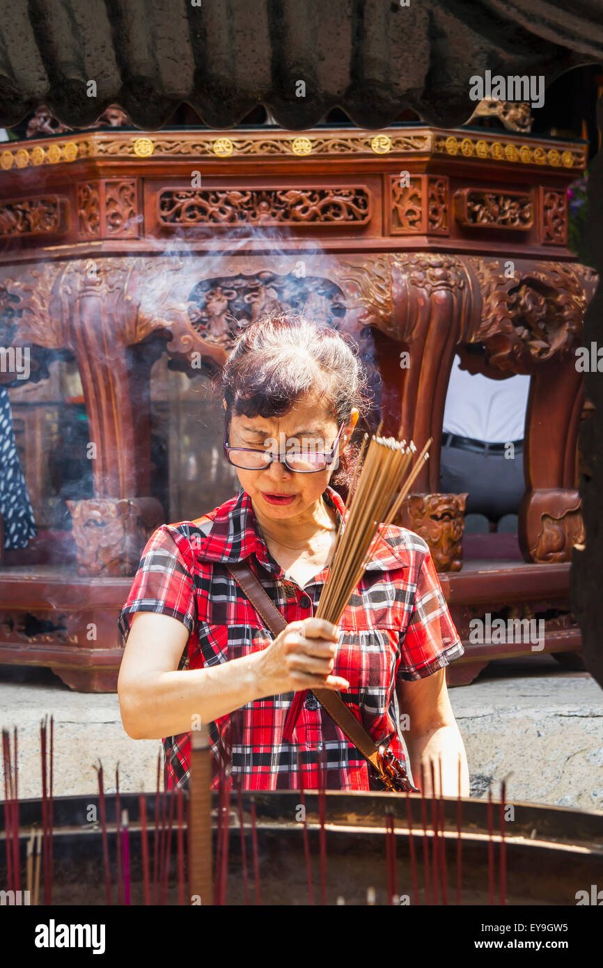 Mujer, quemando incienso en el oficial de God of War Templo; Tainan, Taiwan Foto de stock