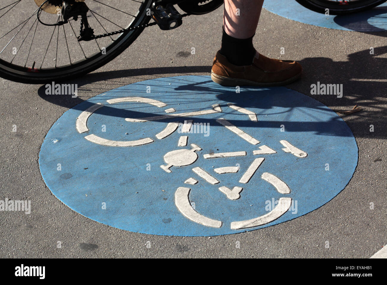 Biker se encuentra junto a una bicicleta azul señal en Viena, Austria. Foto de stock
