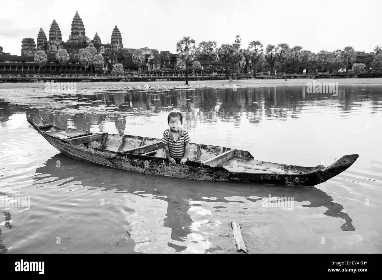 En SIEM REAP, Camboya - 30 de octubre de 2014 Camboya: el joven juega en una embarcación tradicional delante del templo de Angkor Wat. Foto de stock