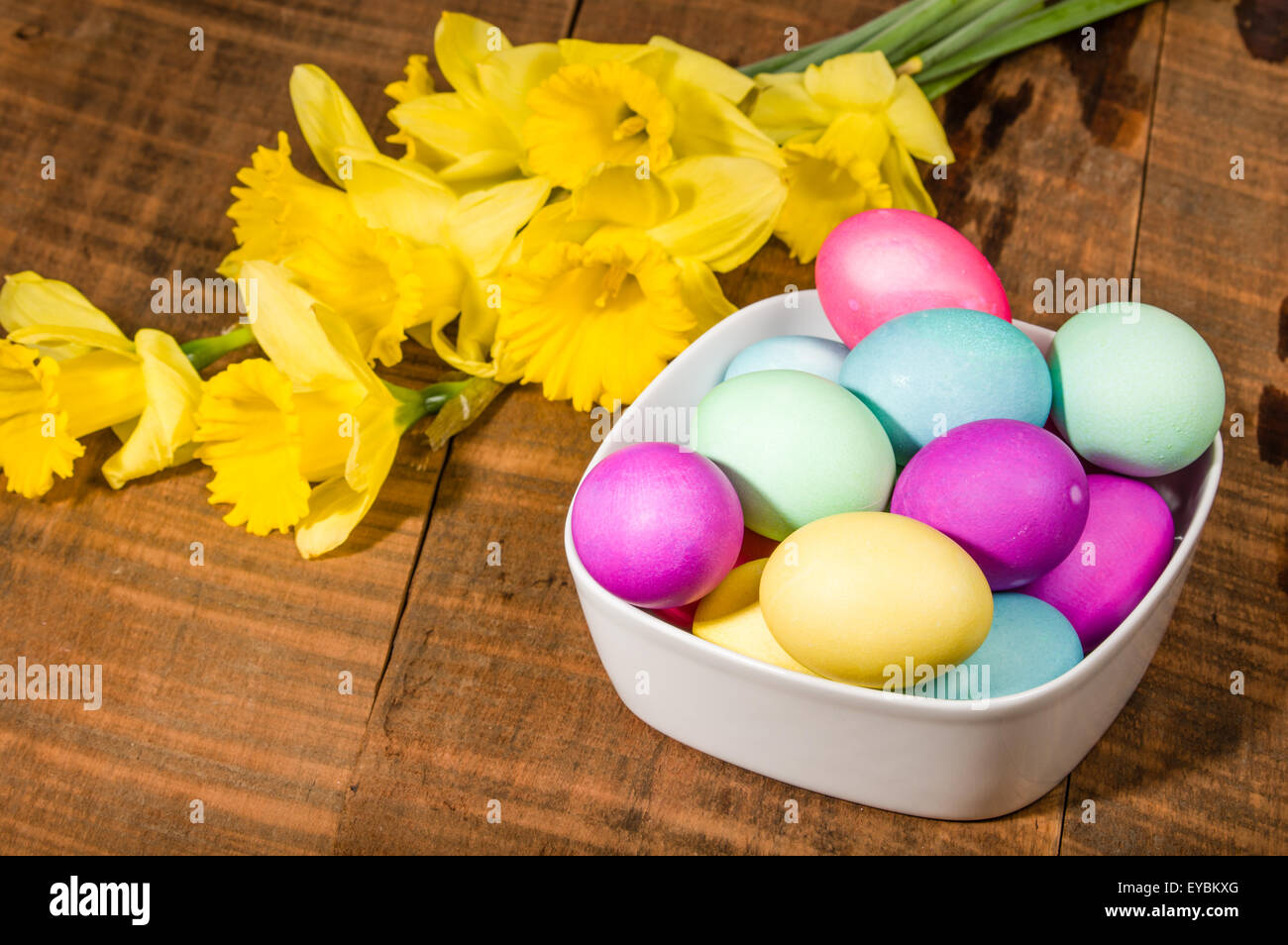 Narciso flores con recipiente de teñido de huevos de Pascua Foto de stock