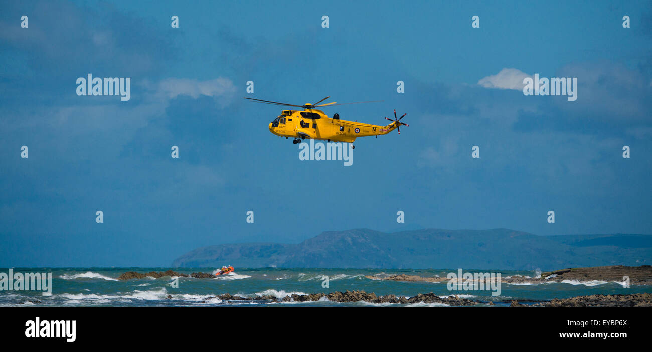 Un amarillo RAF Sea King emeregency helicóptero de rescate aire-mar y bajura salvavidas RNLI costilla off Gales Aberystwyth UK Foto de stock