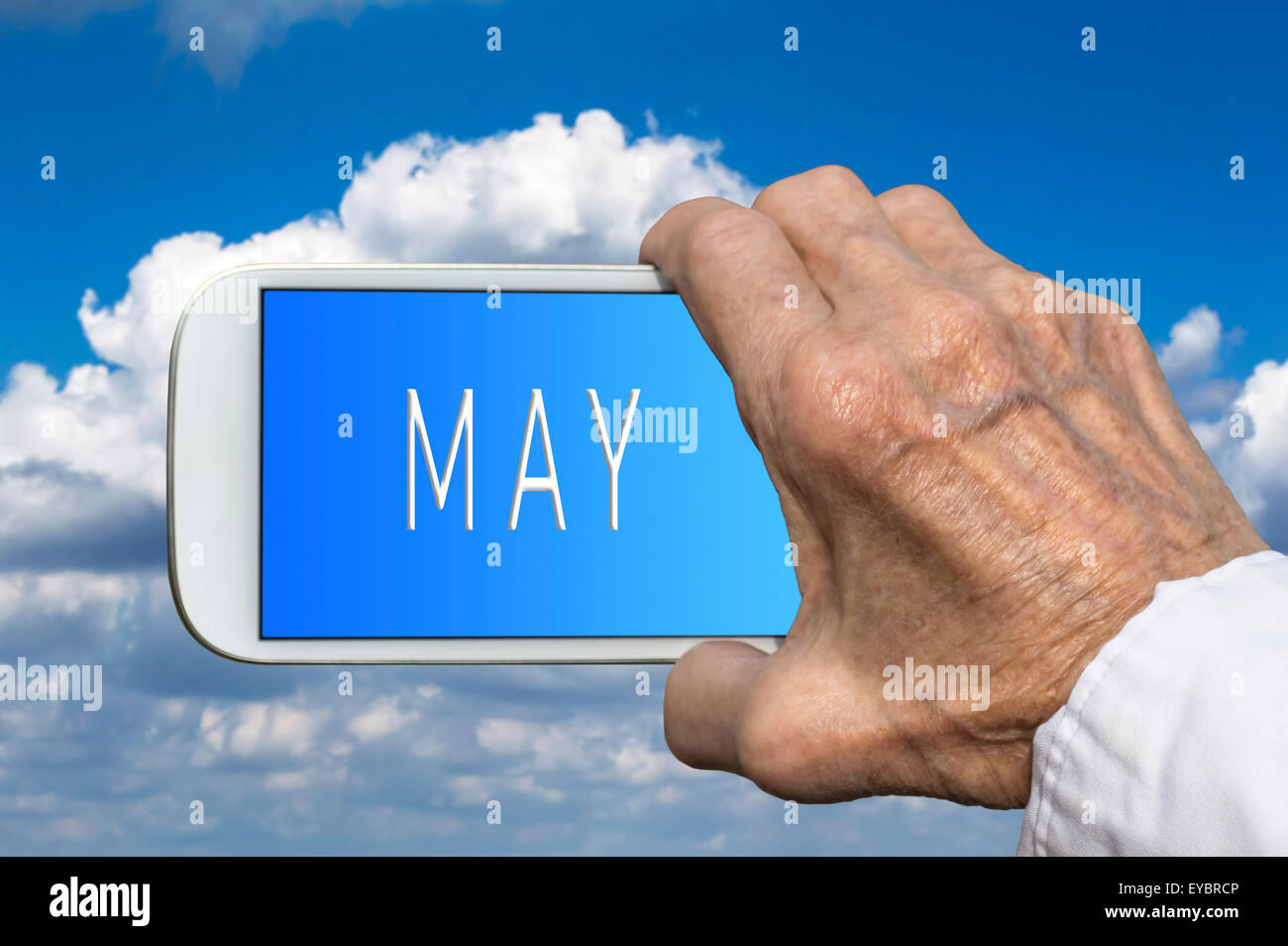 Teléfono inteligente en mano vieja con mes del año - Mayo en pantalla. El enfoque selectivo. Foto de stock