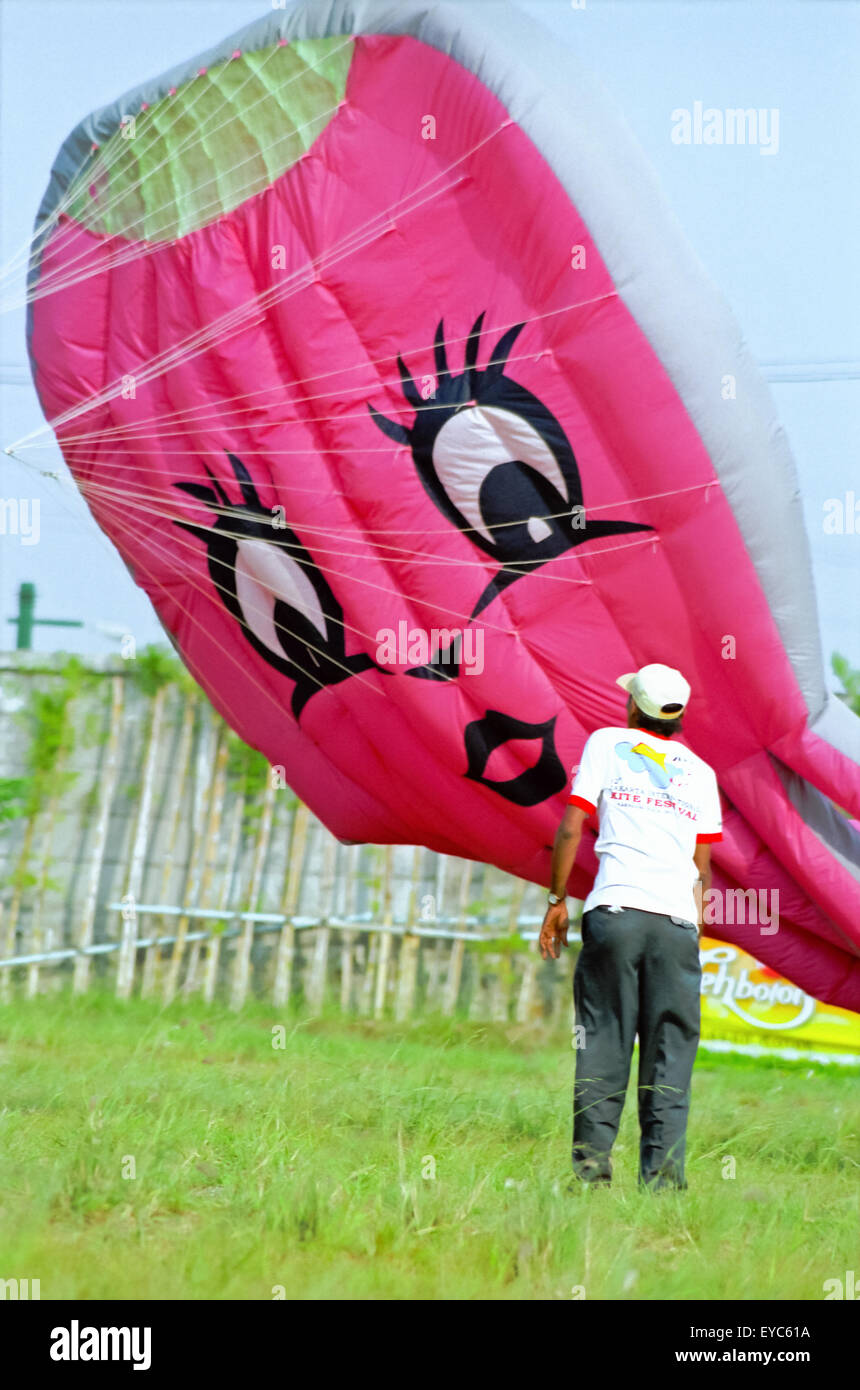 Hombre delante de la cometa humana (más ligera que al aire, con todo el globo de gatitos) durante el Festival Internacional de Kite de Yakarta 2004. Foto de stock