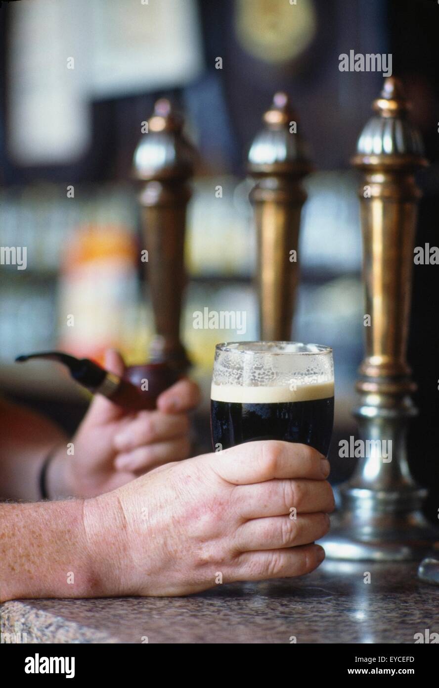 Mano sosteniendo un vaso de cerveza Guinness en un pub irlandés, Irlanda Foto de stock