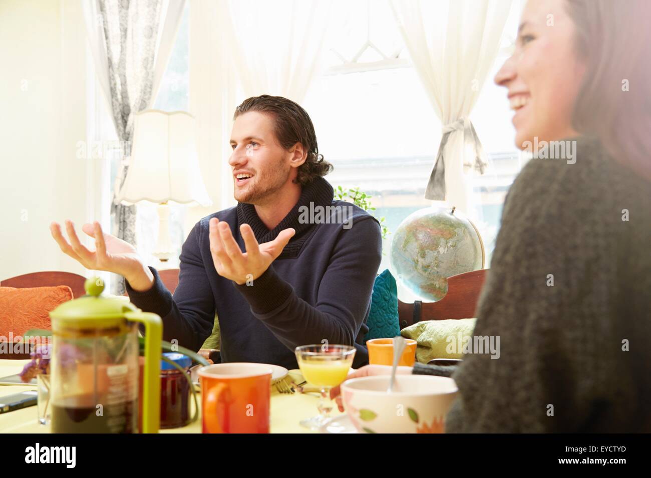 Vista sobre el hombro del joven, explicar con mesa de desayuno Foto de stock