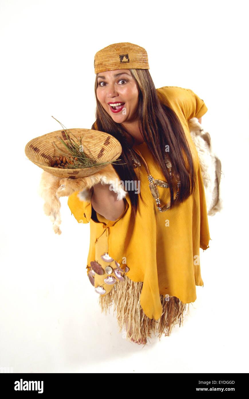 Un Juaneno Acjachemen o mujer americana nativa en traje tradicional muestra una cesta de productos locales en una cesta Foto de stock
