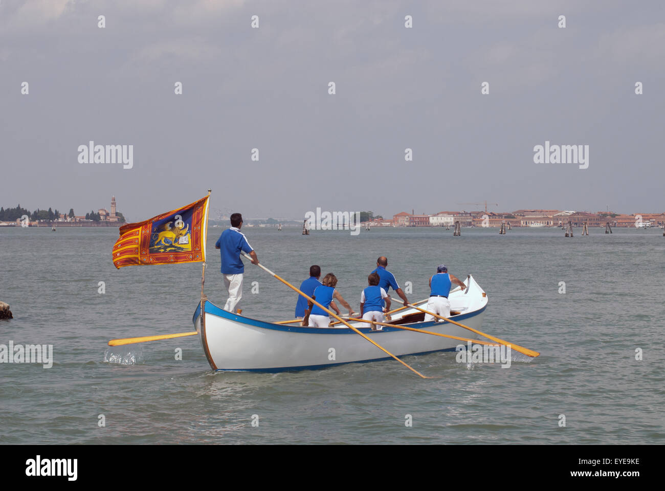 Los remeros en un barco con bandera veneciana con Venecia, en el fondo, la región del Veneto, Italia Foto de stock