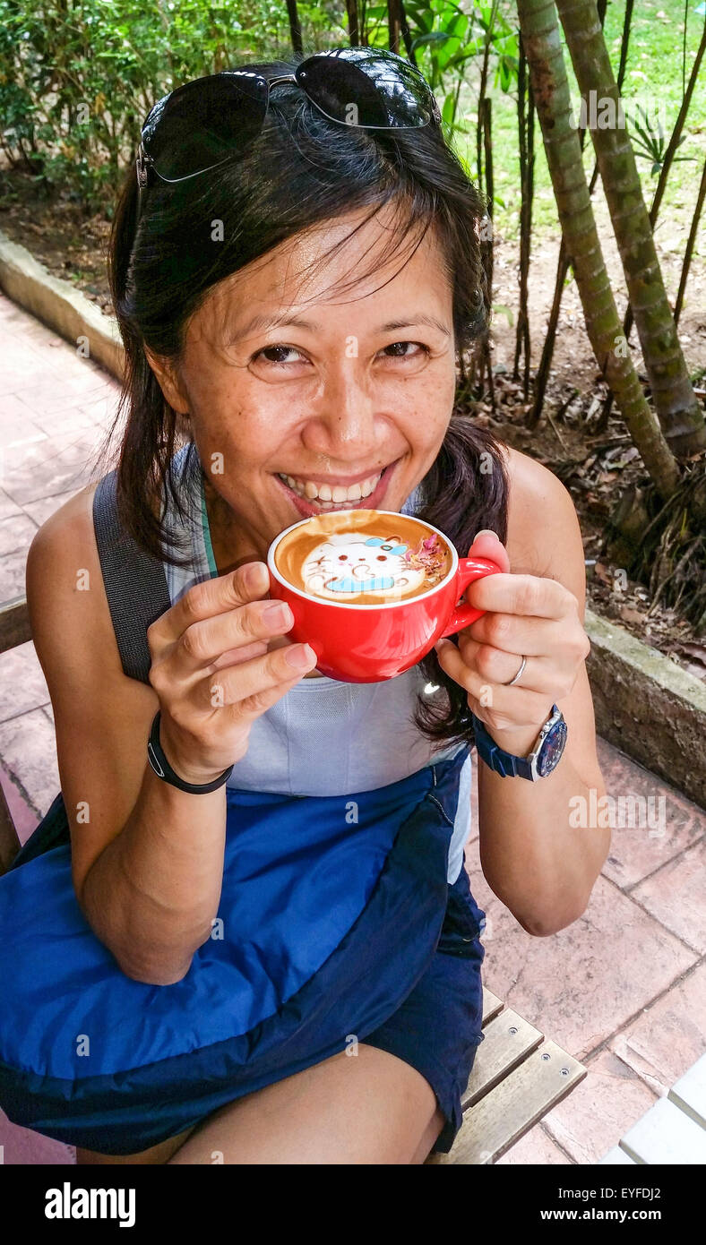 Fancy latte con un diseño de Hello Kitty disfrutada por una mujer en Singapur local repleto de frijoles, una cafetería/deli Foto de stock