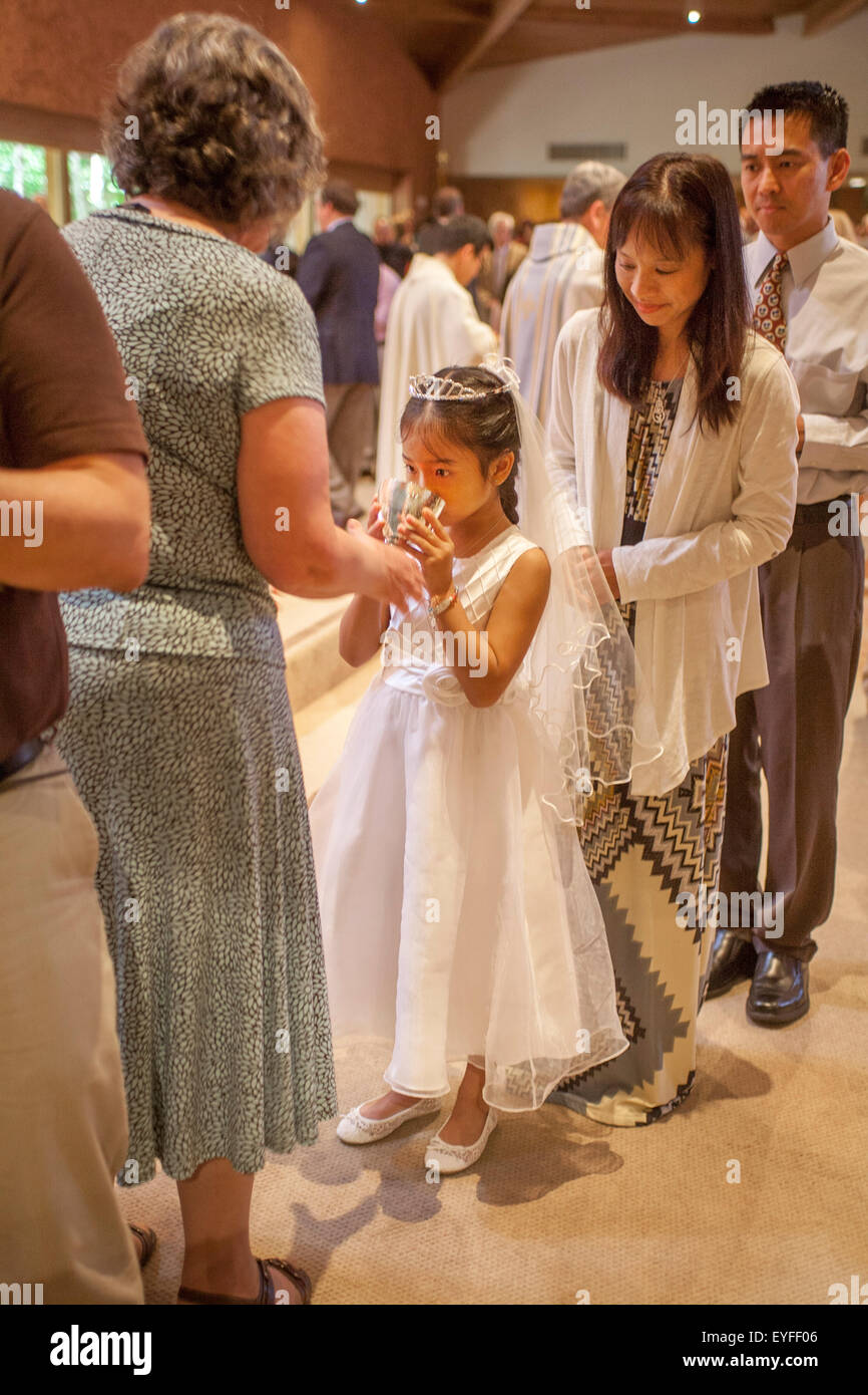 Vistiendo trajes formales, multirracial de niños y sus padres se alinean  para la comunión en la misa en una Laguna Niguel, CA, Iglesia Católica  durante las ceremonias de primera comunión. Nota copa