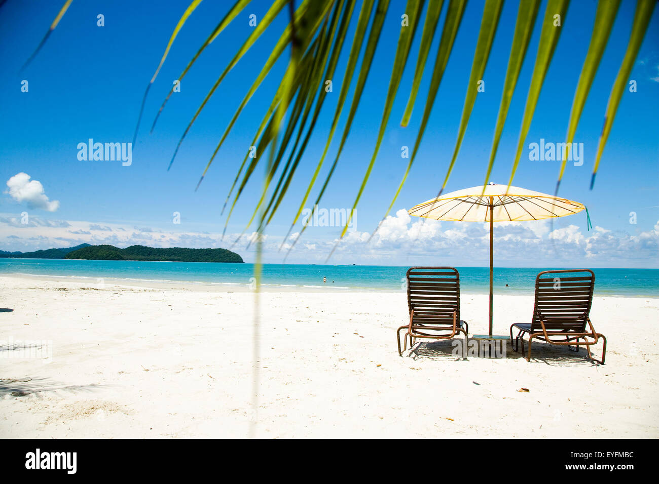 Hamacas bajo una sombrilla en la playa de arena blanca con palmeras con vistas mar azul, playa Cenang; Pulau Langkawi, Malasia Foto de stock