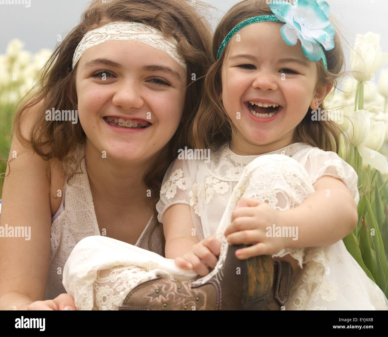 Las niñas en campo tulip vestida de blanco vestidos bonitos y cintillos y botas  vaqueras Fotografía de stock - Alamy