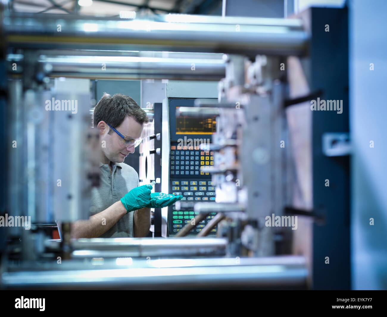 Trabajador de inspección de piezas de la máquina de moldeo de plástico por inyección en fábrica de plásticos Foto de stock