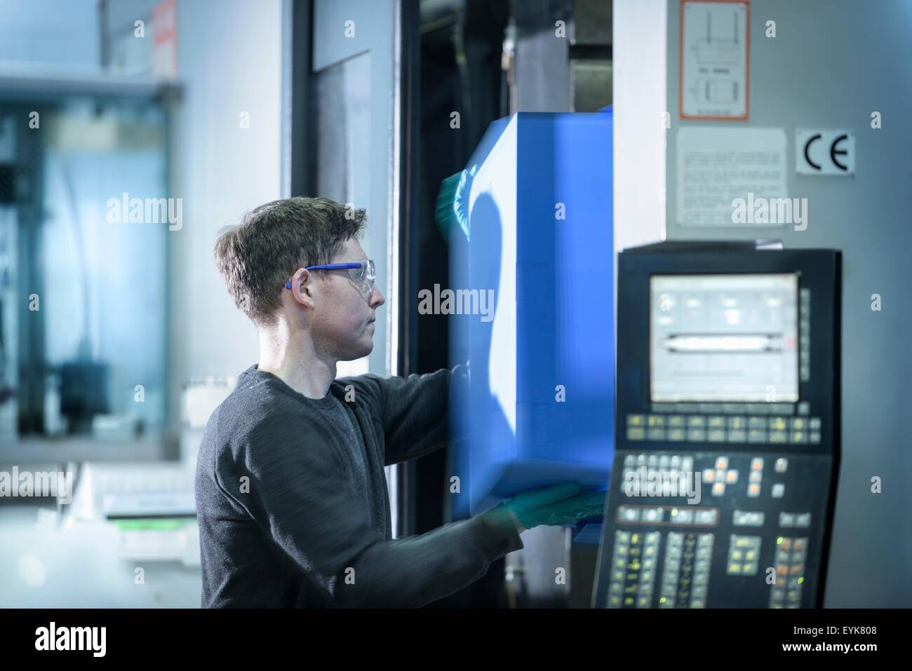 Trabajador eliminando parte de plástico de la máquina de moldeo por inyección en fábrica de plásticos Foto de stock