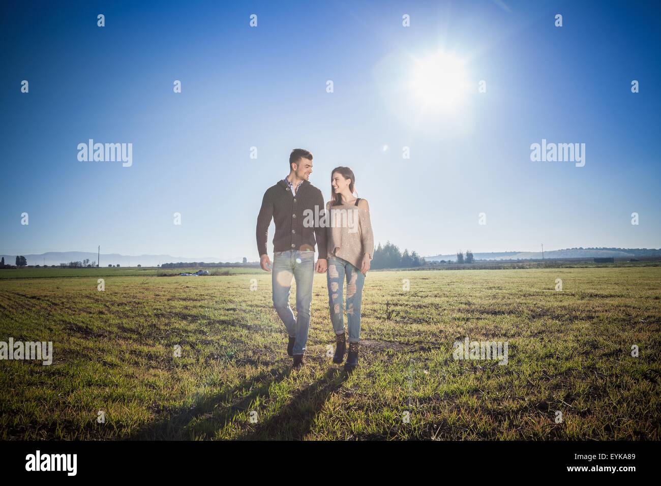 Joven pareja tomados de las manos en el campo Foto de stock