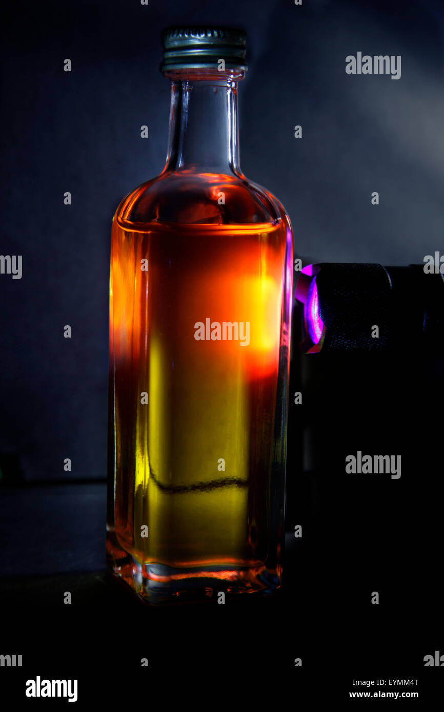 UL brilla la luz en una pequeña botella de aceite de oliva, creando la fluorescencia roja Foto de stock