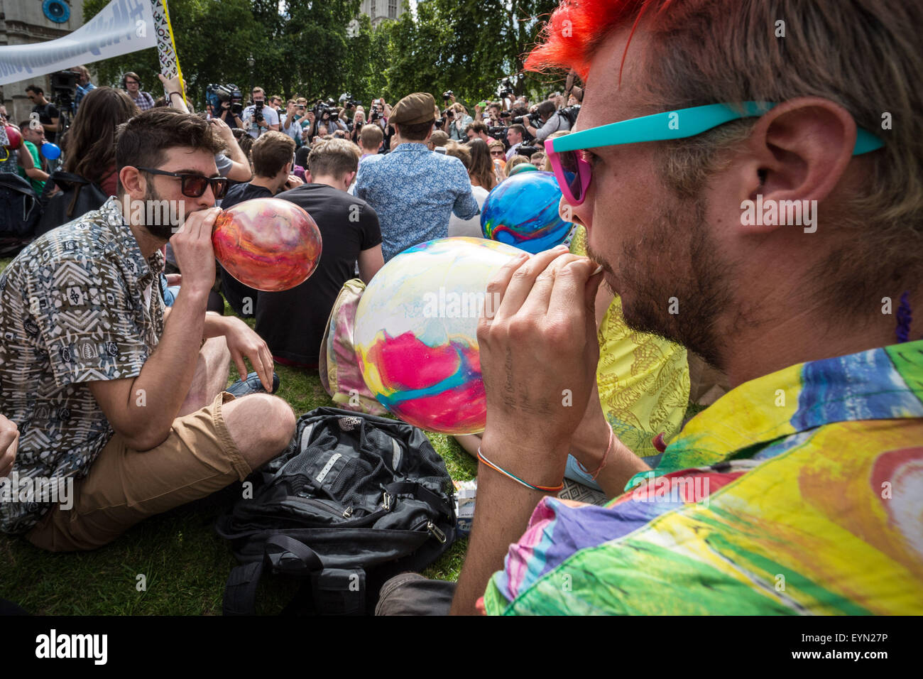 Londres, Reino Unido. El 1 de agosto de 2015. Los activistas inhalar globos inflados con óxido nitroso, conocido comúnmente como "gas de la Risa" para obtener alta durante una protesta en la Plaza del Parlamento de Westminster contra un proyecto de ley que apunta a hacer la venta de cualquier sustancia psicoactiva ilegal. Crédito: Guy Corbishley/Alamy Live News Foto de stock