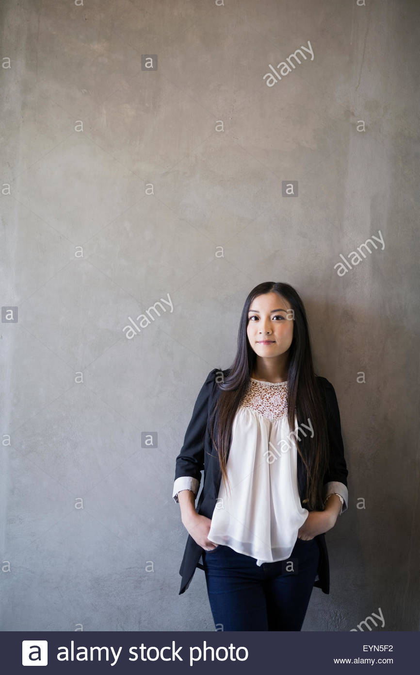 Retrato mujer confiada con las manos en los bolsillos de fondo gris Foto de stock