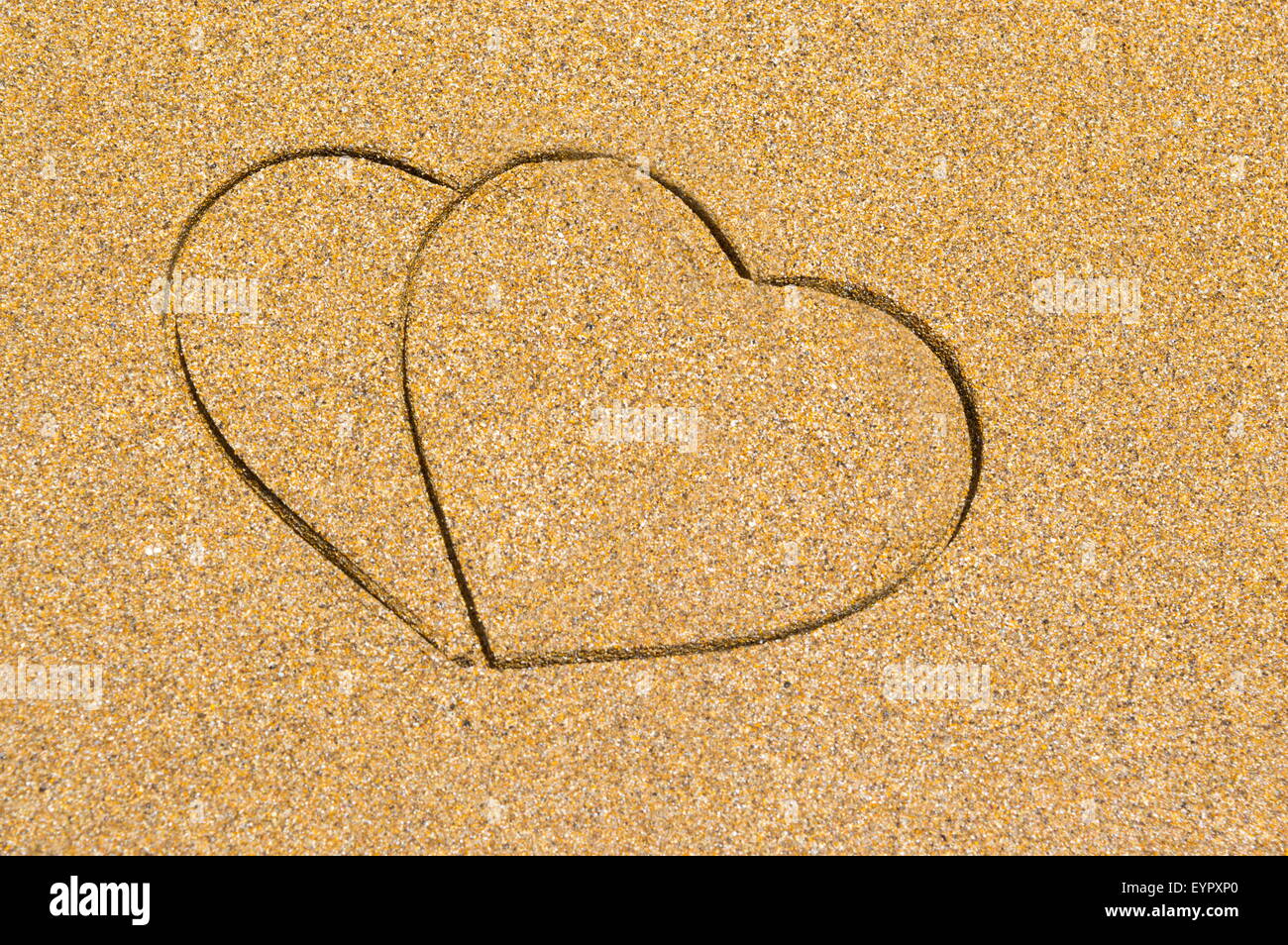 Dos forma corazón grabado en una playa de arena húmeda. Fondo de vacaciones de verano Foto de stock