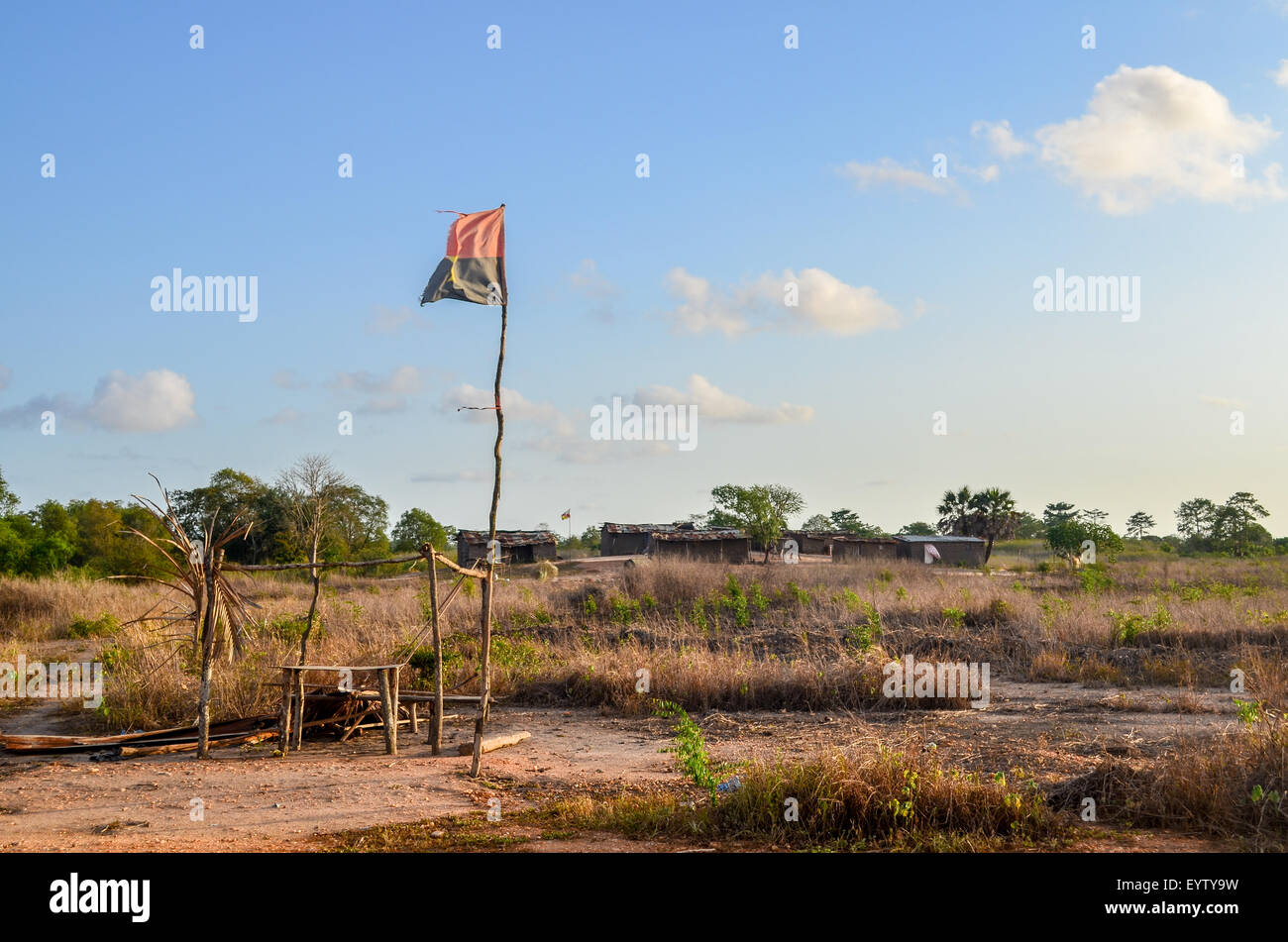 Pabellón de Angola en un palo de madera en el cielo azul de la campiña de Angola Foto de stock