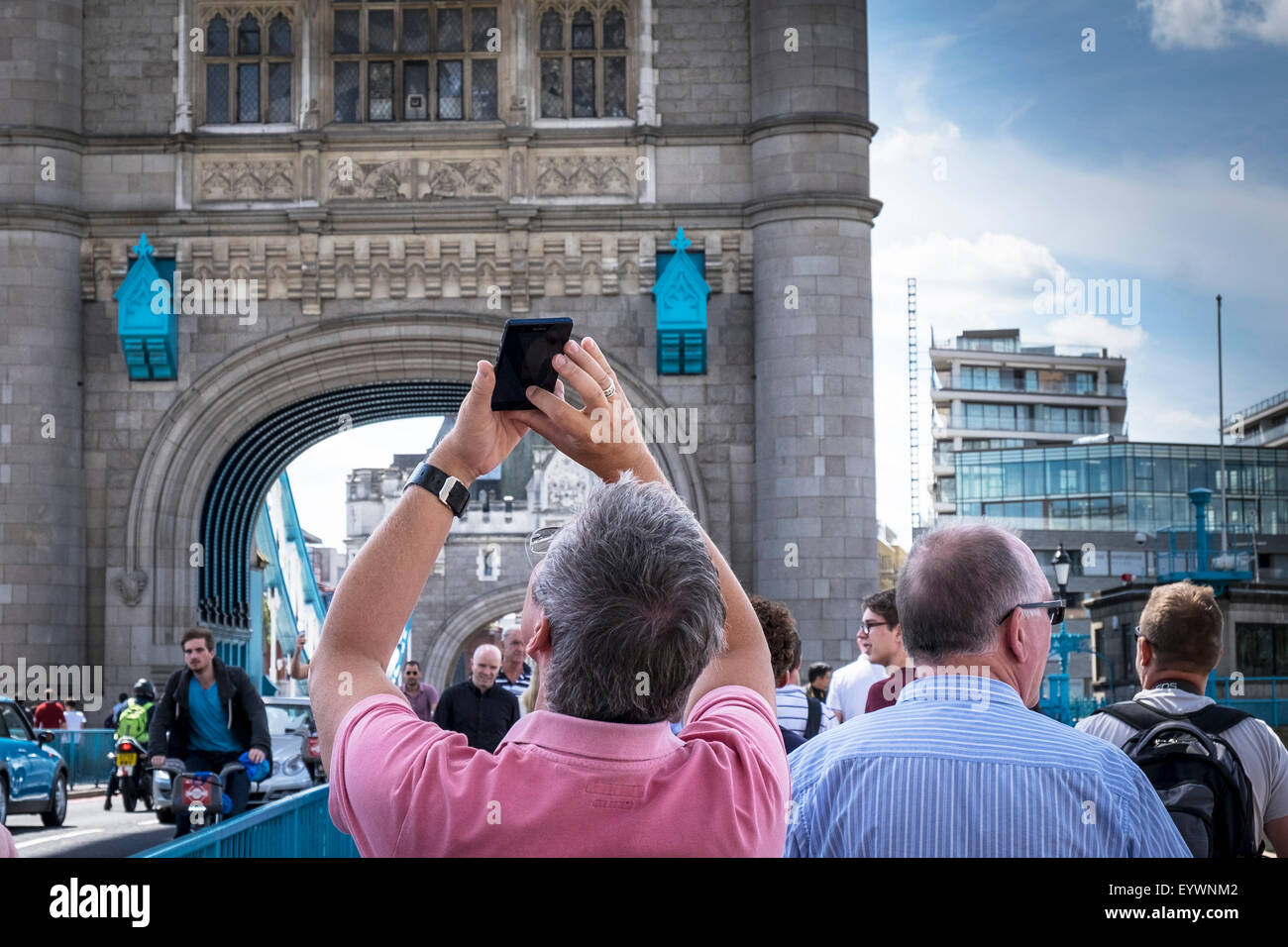 Un turista utiliza su teléfono móvil para fotografiar el Tower Bridge de Londres. Foto de stock