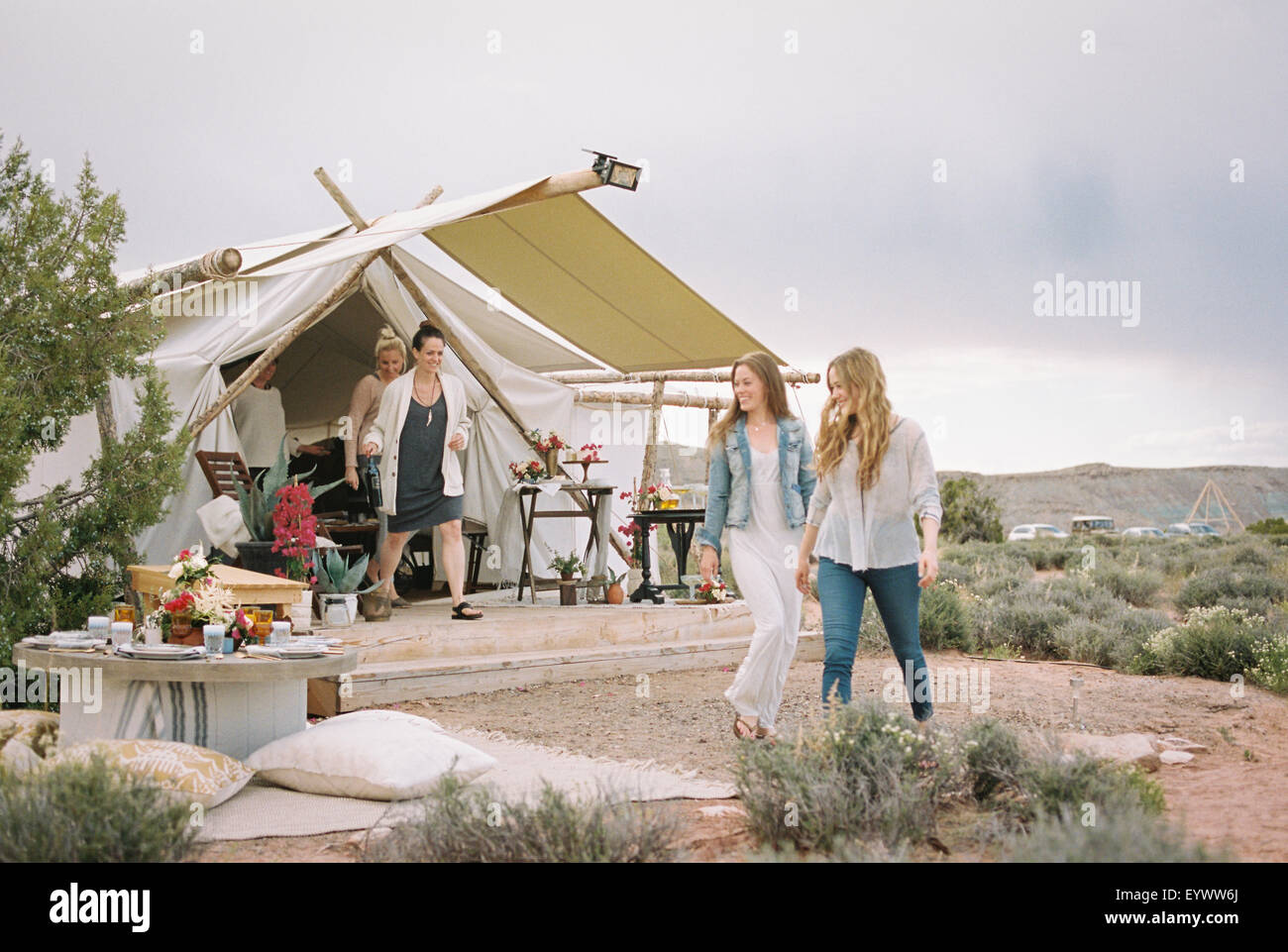 Grupo de amigos disfrutando de una comida al aire libre en un desierto, una carpa en el fondo. Foto de stock
