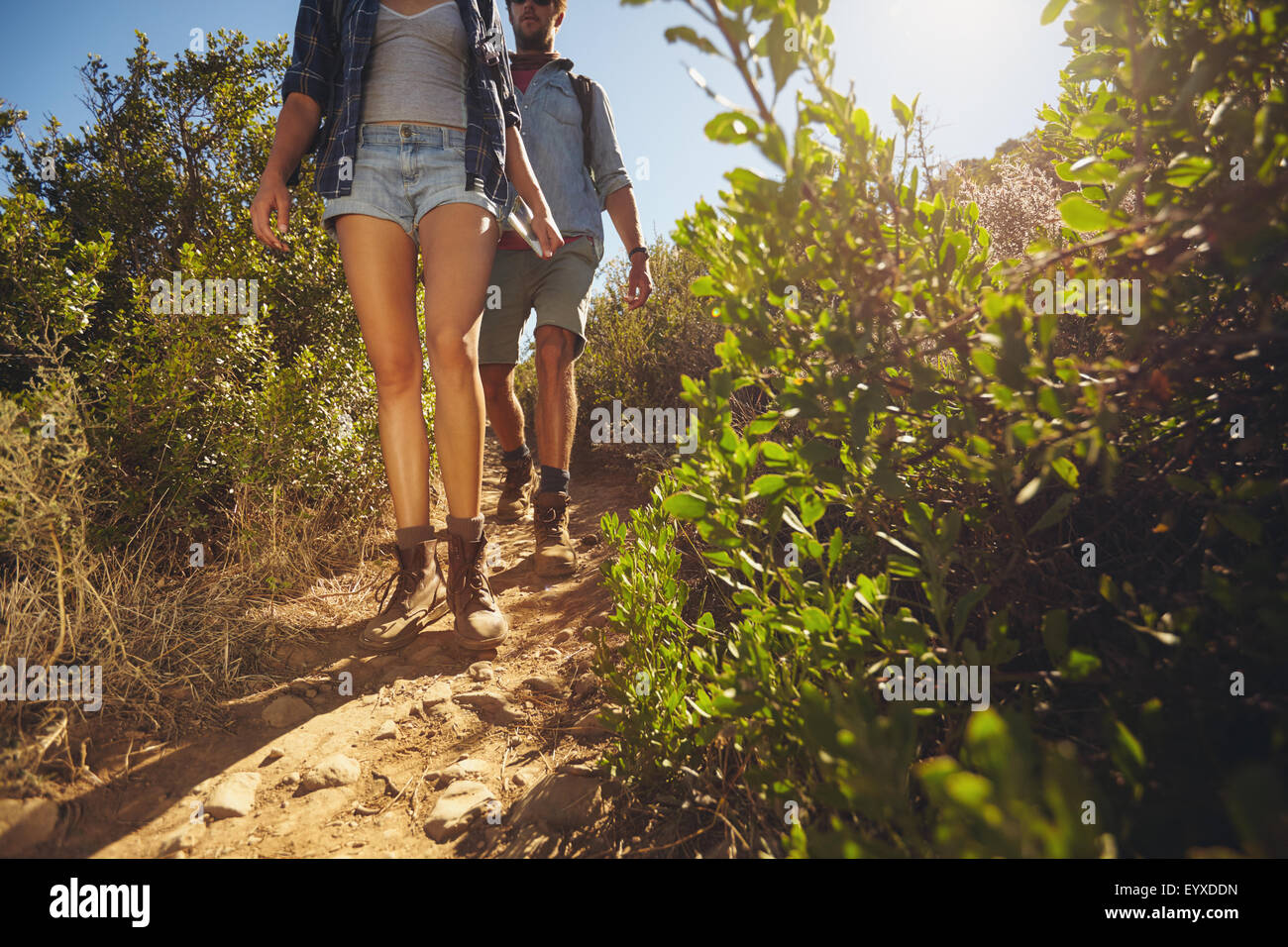 Excursionistas caminando por país trail. Dos jóvenes senderismo en las montañas de día soleado. Captura recortada se centran en las piernas. Foto de stock