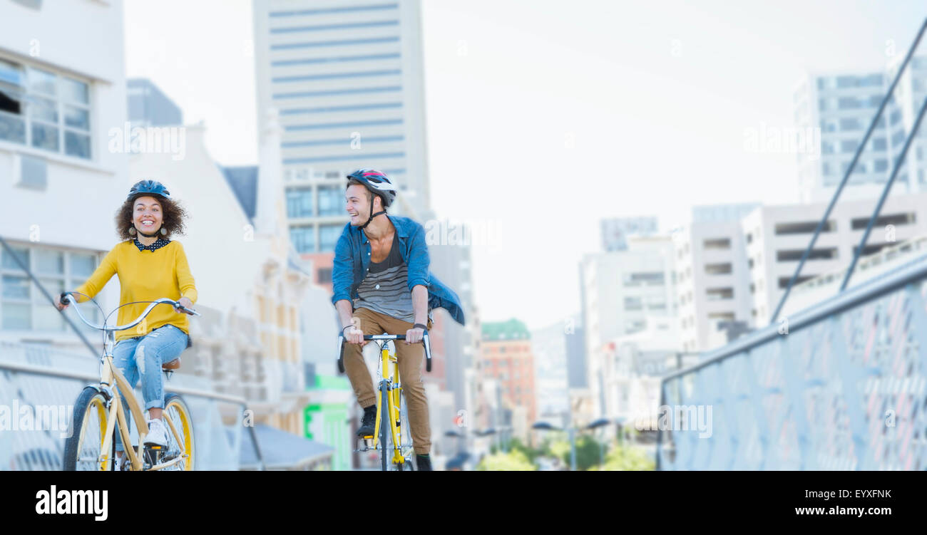 Amigos con cascos en bicicleta a través de pasarela urbana Foto de stock